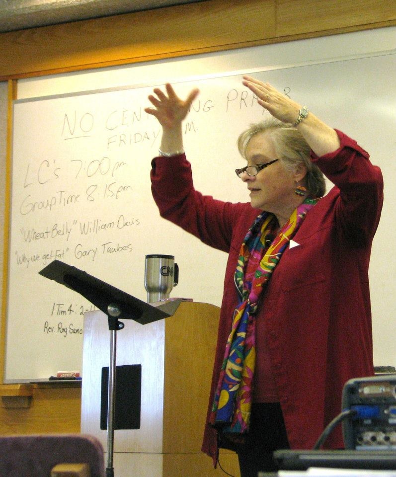 Woman lecturing at podium, hands raised